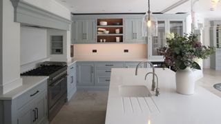 gray kictchen with white marble countertops with concealed kitchen storage in the chimney breast