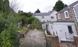 A small car parking space at the front of a house and a small garden