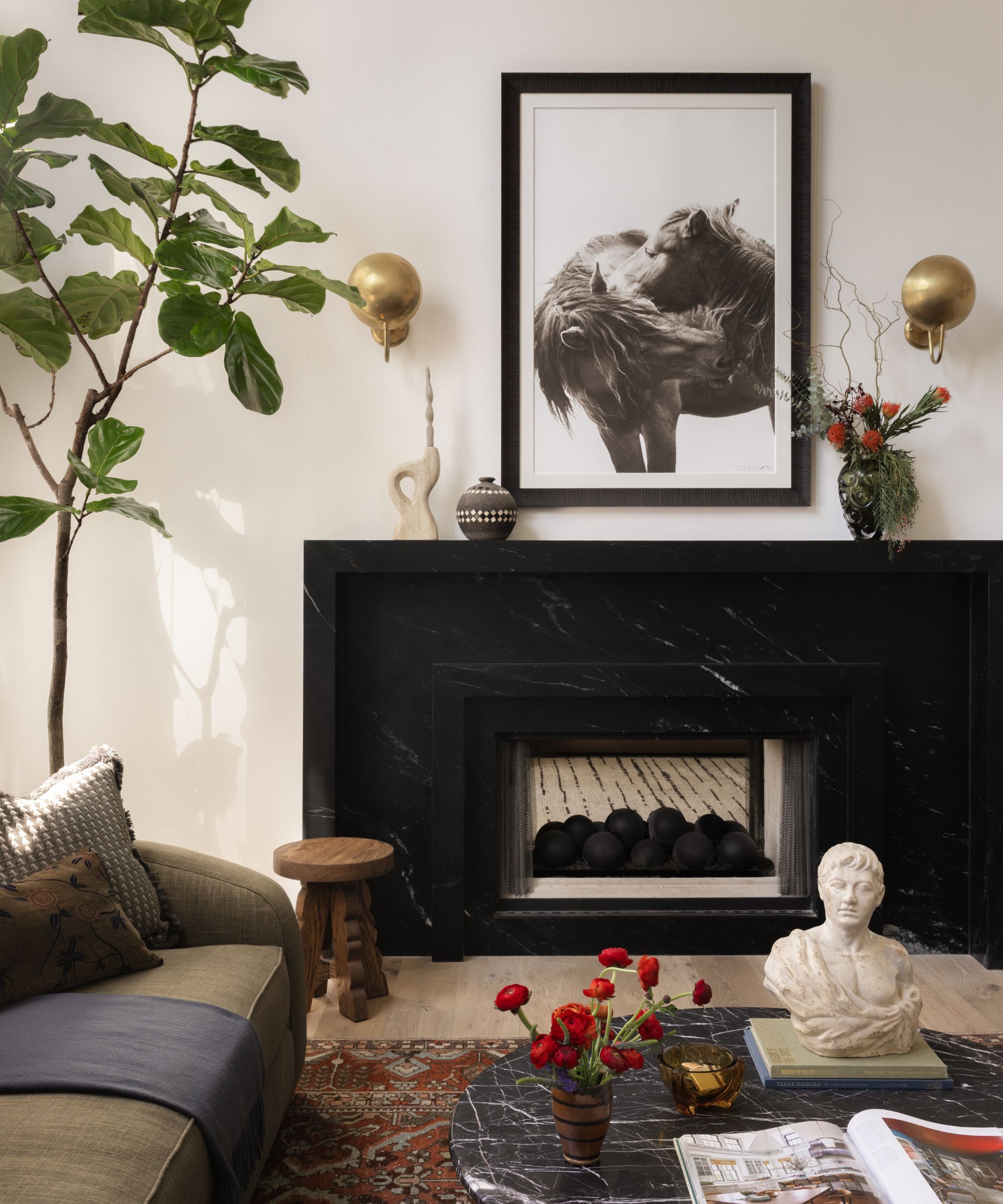 a close up of the black soapstone fireplace in a neutral living room with a vintage rug and green couch