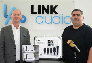 Two men from Audix and Link Audi stand together displaying products for their new partnership.