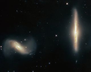While it's common for galaxies to coexist peacefully in the same cosmic neighborhood, these two galaxies are a bit too close for comfort. The galaxies NGC 6286 (right) and NGC 6285 (left), collectively known as Arp 293, are tugging at each other with their mutually strong gravitational attraction, dragging wisps of gas and dust out from the galaxies and into interstellar space. This causes the galaxies to appear "smudged" and blurred from our perspective on Earth. The Hubble Space Telescope captured this image of the galactic pair, which are located more than over 250 million light-years from Earth in the constellation Draco.