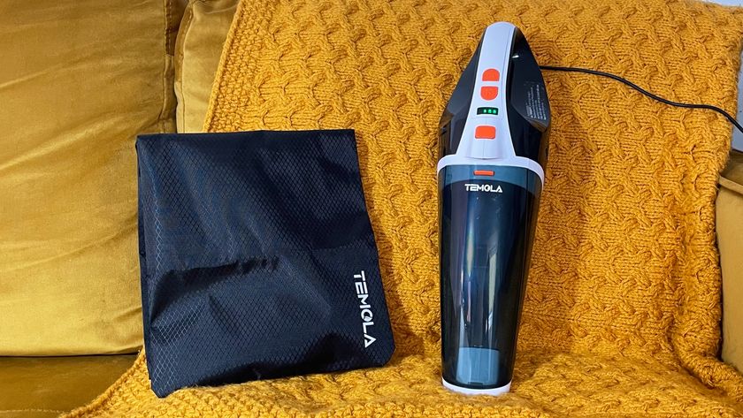 The Temola TS20BS handheld vacuum and storage bag on a mustard color blanket.