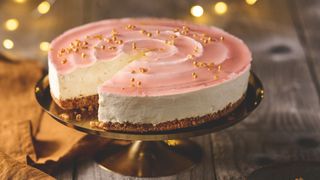 A Baileys cheesecake on a gold cake stand with a burnt orange linen napkin to one side.