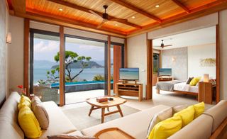 Suite at the Habita hotel, lounge with cream sofas, yellow cushions, wooden ceiling overlooking bay