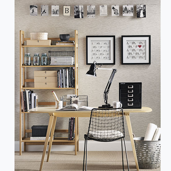 home office with textured wall and desk with black lamp and chair and ladder shelves