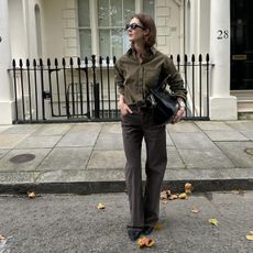 A photo of Olivia Wayman wearing a green shirt, gray jeans, a black tote bag, and black flats.