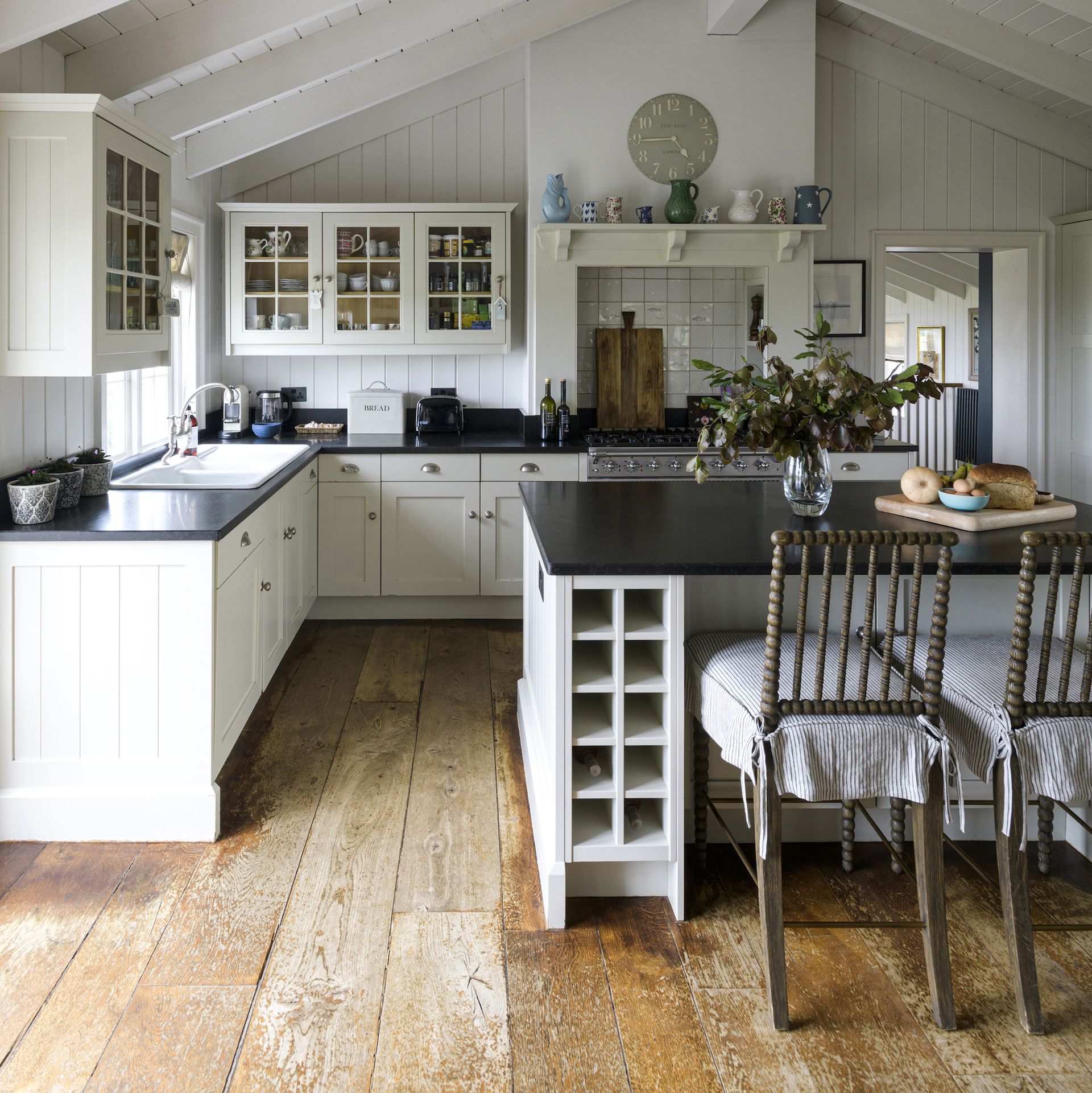 white farmhouse kitchen with black worktops and island with wine rack