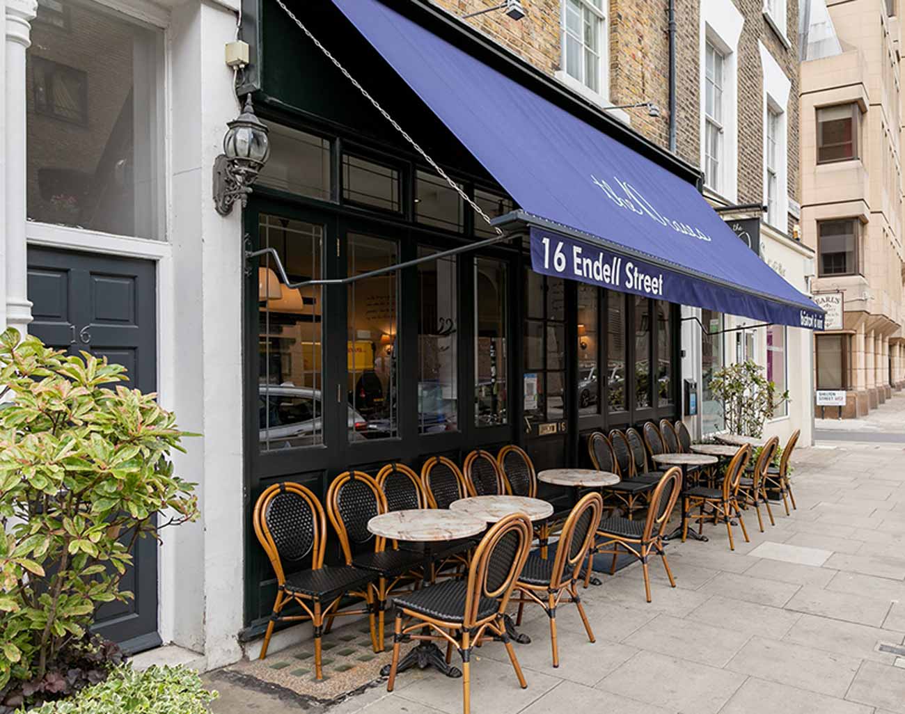 A pavement outside a wine bar with tables and chairs