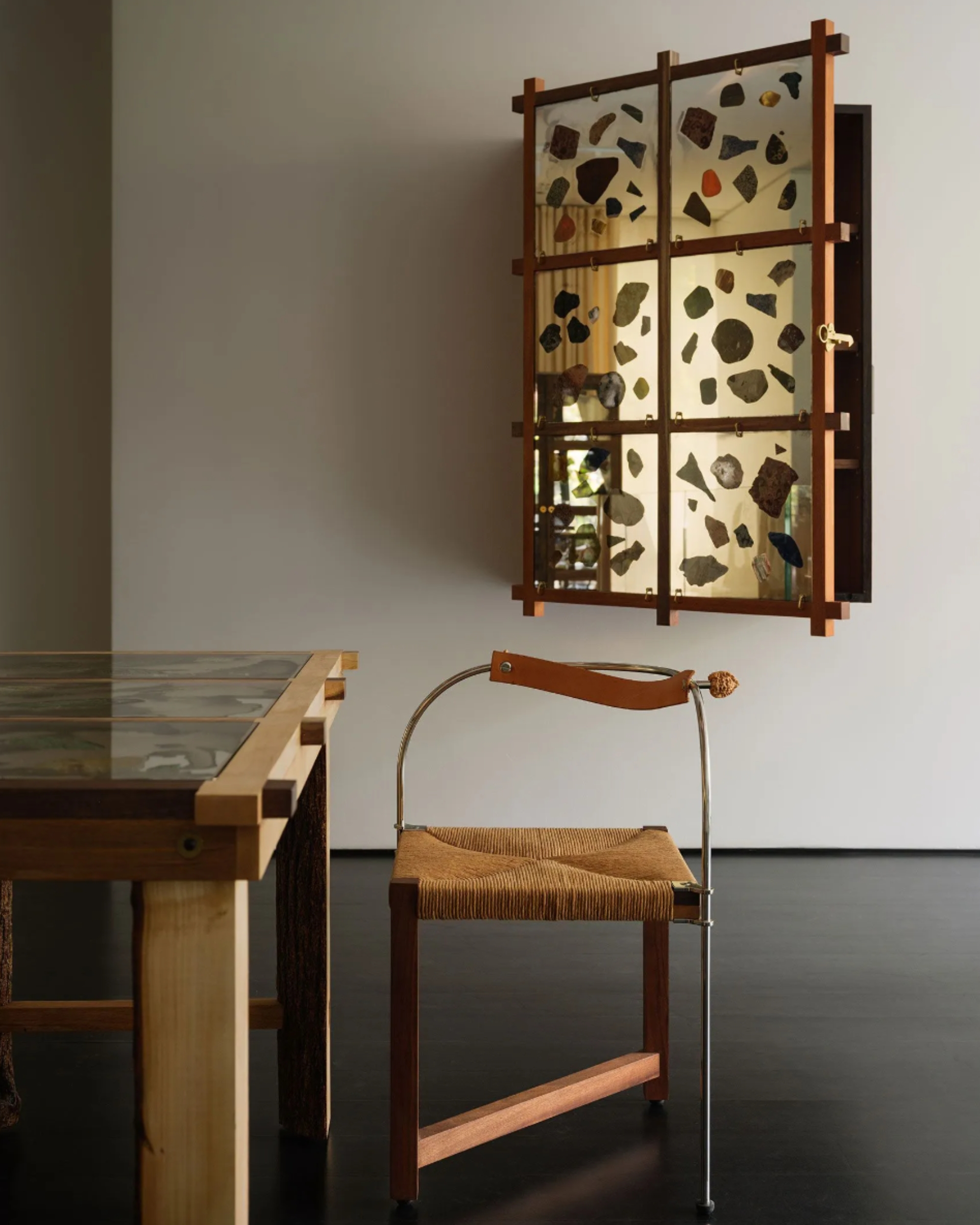 Image of a unique chair by a table with a mirrored floating cabinet hanging on the back wall.