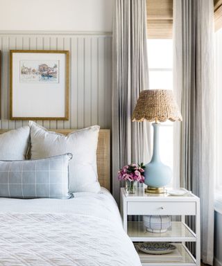 Neutral bedroom with striped wallpaper and bedside table with large bedside light