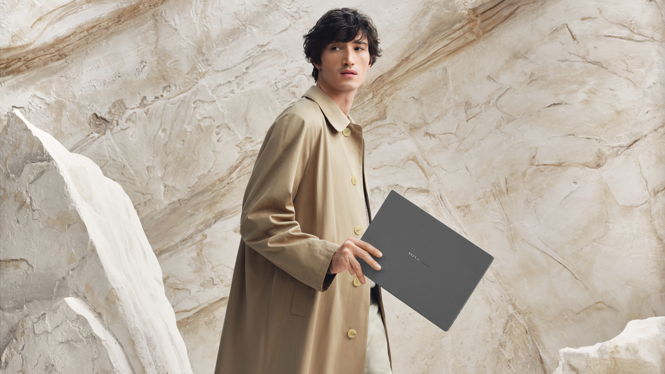 A man carries an Asus Zenbook A16 laptop