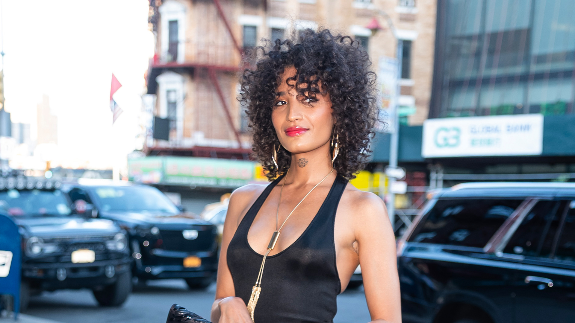 Indya Moore wearing a black long dress with violet pointed toe heels 