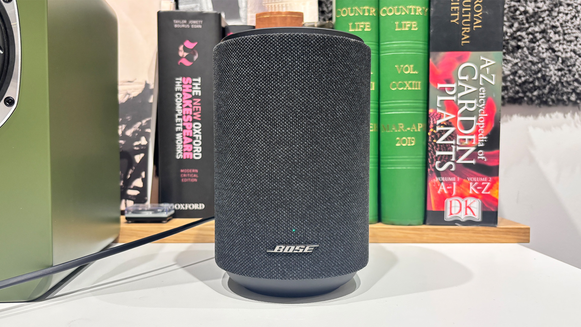 Bose Lifestyle Ultra Speaker wireless speaker in front of busy bookshelf