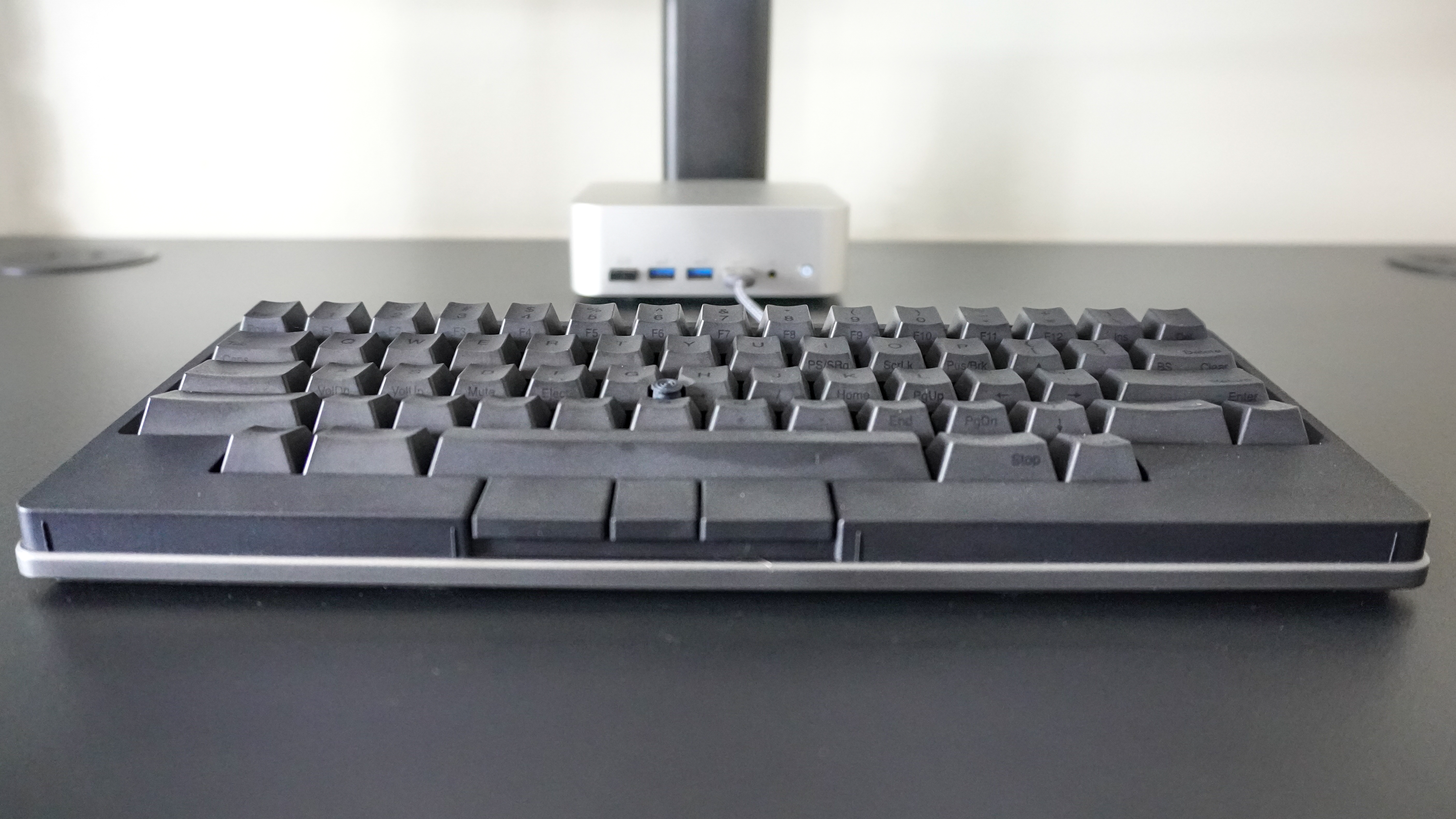 An HHKB Studio keyboard on a desk in front of a mini PC