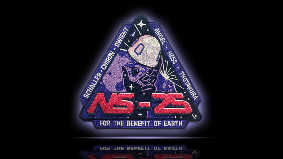 A triangular Blue Origin NS-25 mission patch with a capsule floating out of a stylized hand filled with stars.