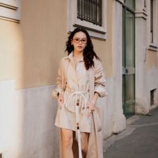 Woman wears trench coat with shirt dress in Milan.