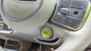 Close-up of a yellow boost button on a cream leather steering wheel