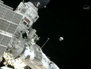 Photo of cosmonaut throwing spherical satellite into orbit.