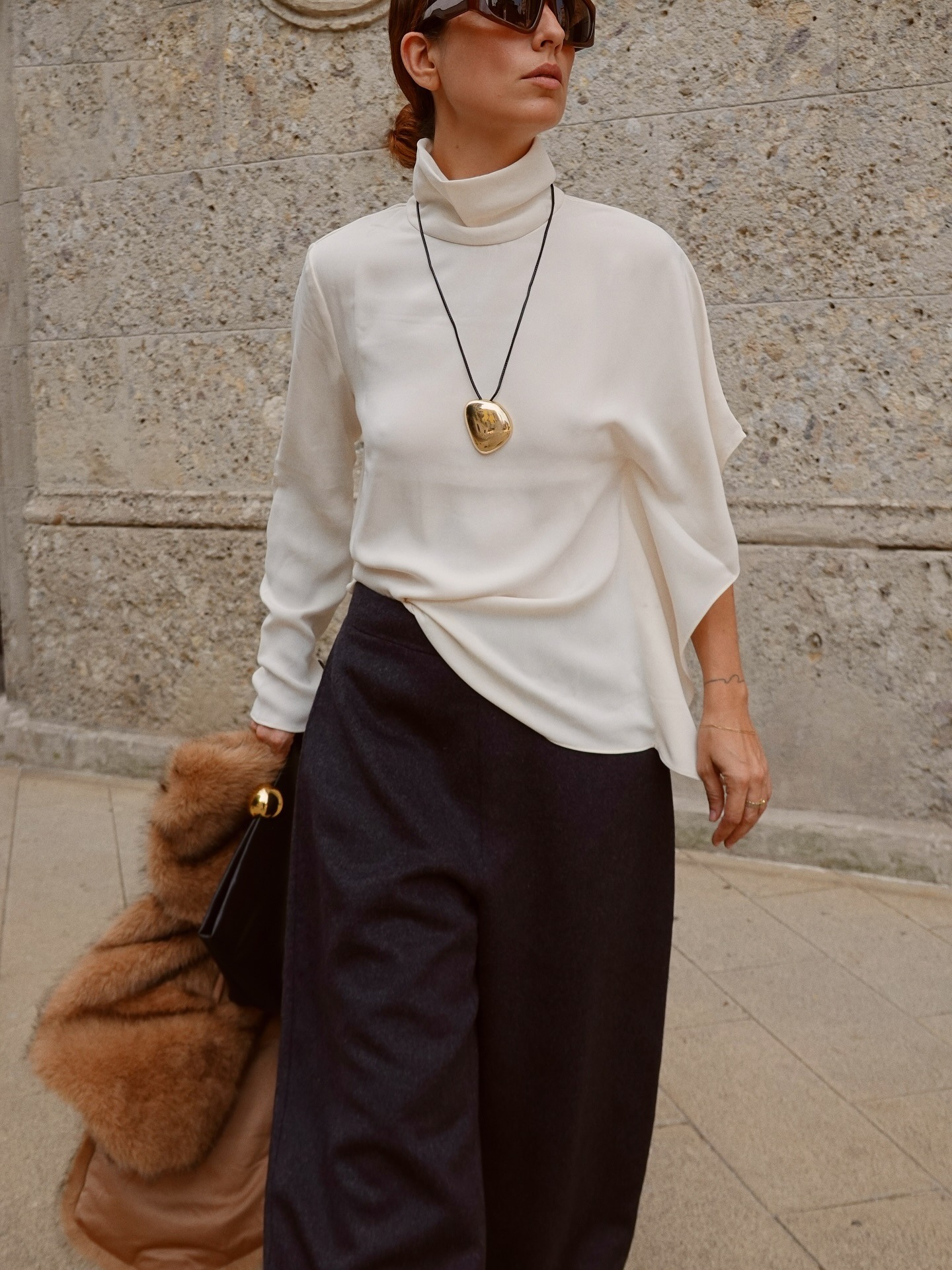 Woman in a white sweater with a long pendant necklace
