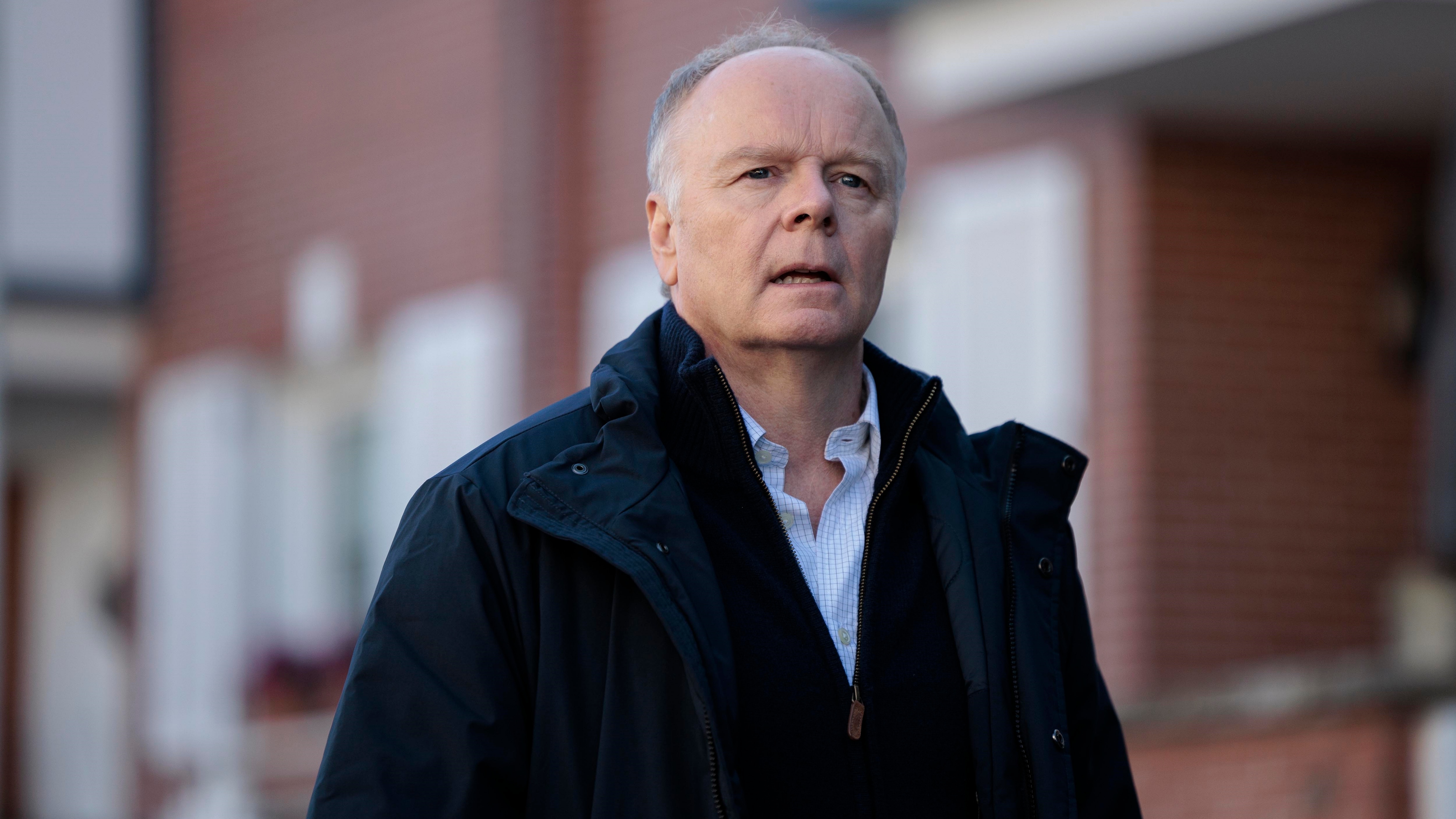 Huw looking worried as he stands on the street in a dark coat