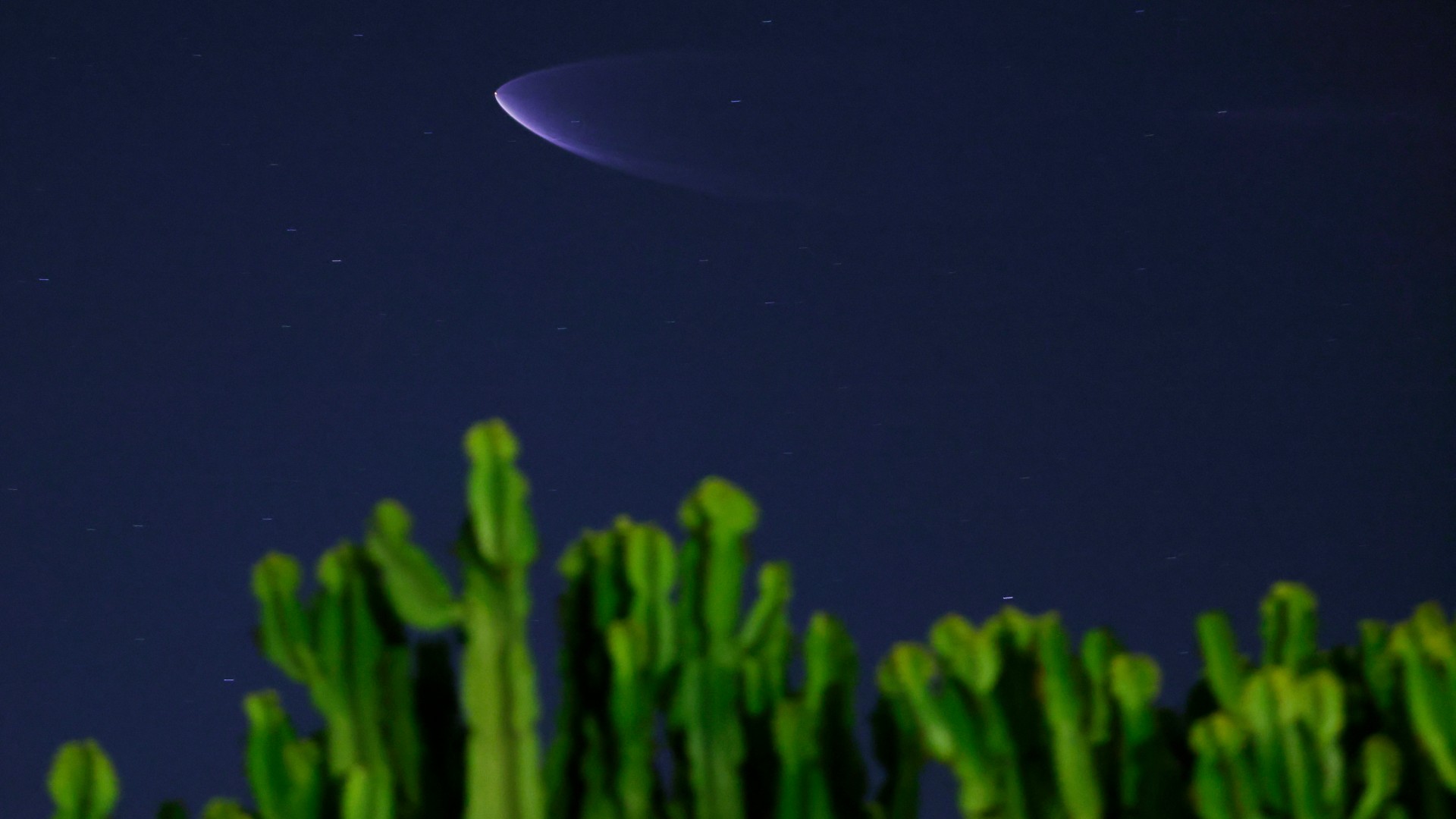 una nube azul en forma de cono en el cielo sobre cactus verdes