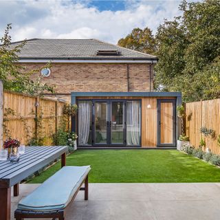 Green Retreats garden room at bottom of garden surrounded with wooden fences with climbing plants