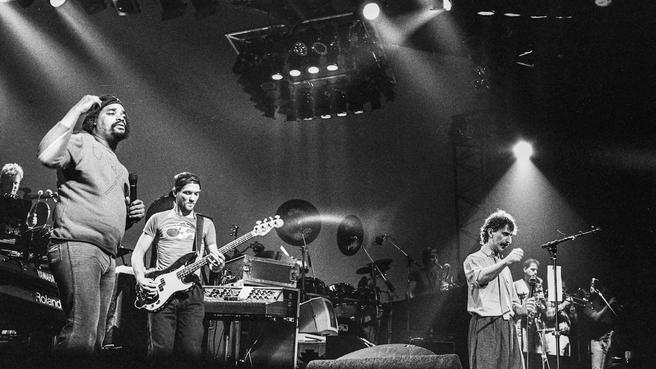 Frank Zappa (1940 - 1993) (fore, right, in spotlight) as he performs on stage, with his band, at the Beacon Theatre, New York, New York, February 2, 1988.