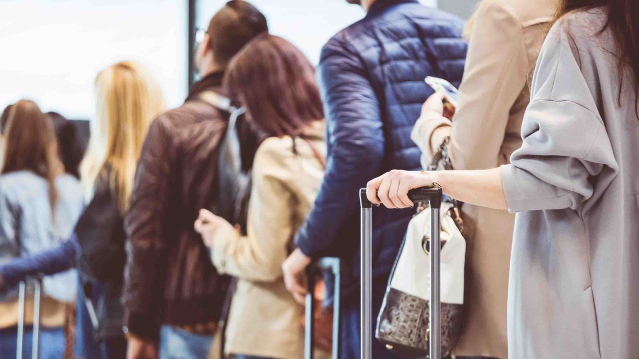 photo of travelers waiting on line at an airport