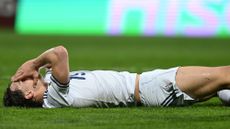 Italy striker Pio Esposito lying on the pitch with his hands covering his face