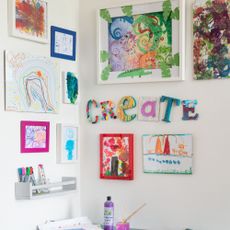 An arts and crafts corner in a kids' playroom with artwork displayed on the walls