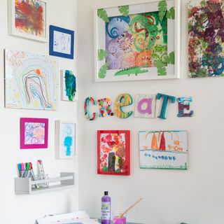 An arts and crafts corner in a kids' playroom with artwork displayed on the walls