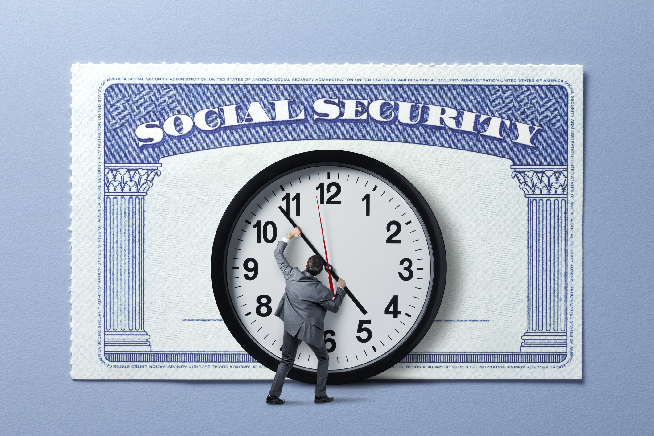 A man in a business suit tries to turn back a giant clock with a Social Security card in the background.