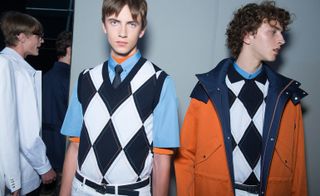 Two male models wearing patterned clothing by Dior Homme in black, white and orange.