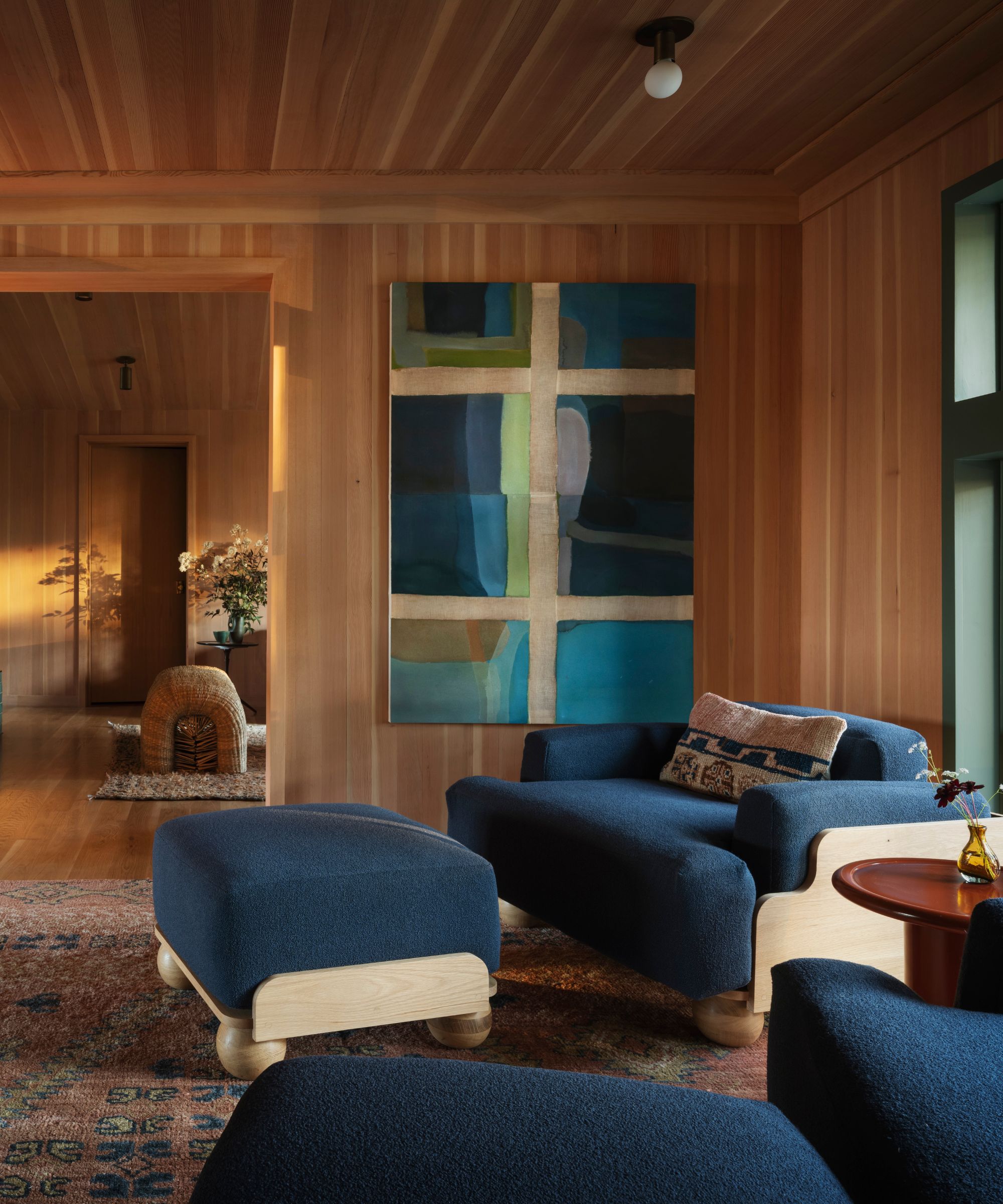 wood clad landing seating area with blue armchairs and a large painting