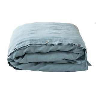 A folded linen duvet cover with button closures in a washed, pale, dusty blue shade
