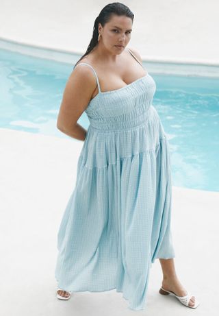 model wears blue shirred maxi sun dress by the pool while wearing white slide on kitten mules 