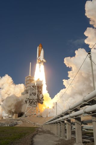 With pipes in the foreground, space shuttle Discovery ignites for liftoff from Launch Pad 39A at NASA's Kennedy Space Center in Florida, beginning its final flight, the STS-133 mission,