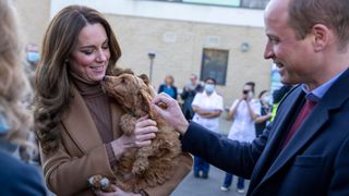 Kate Middleton holding a poodle with Prince William by her side