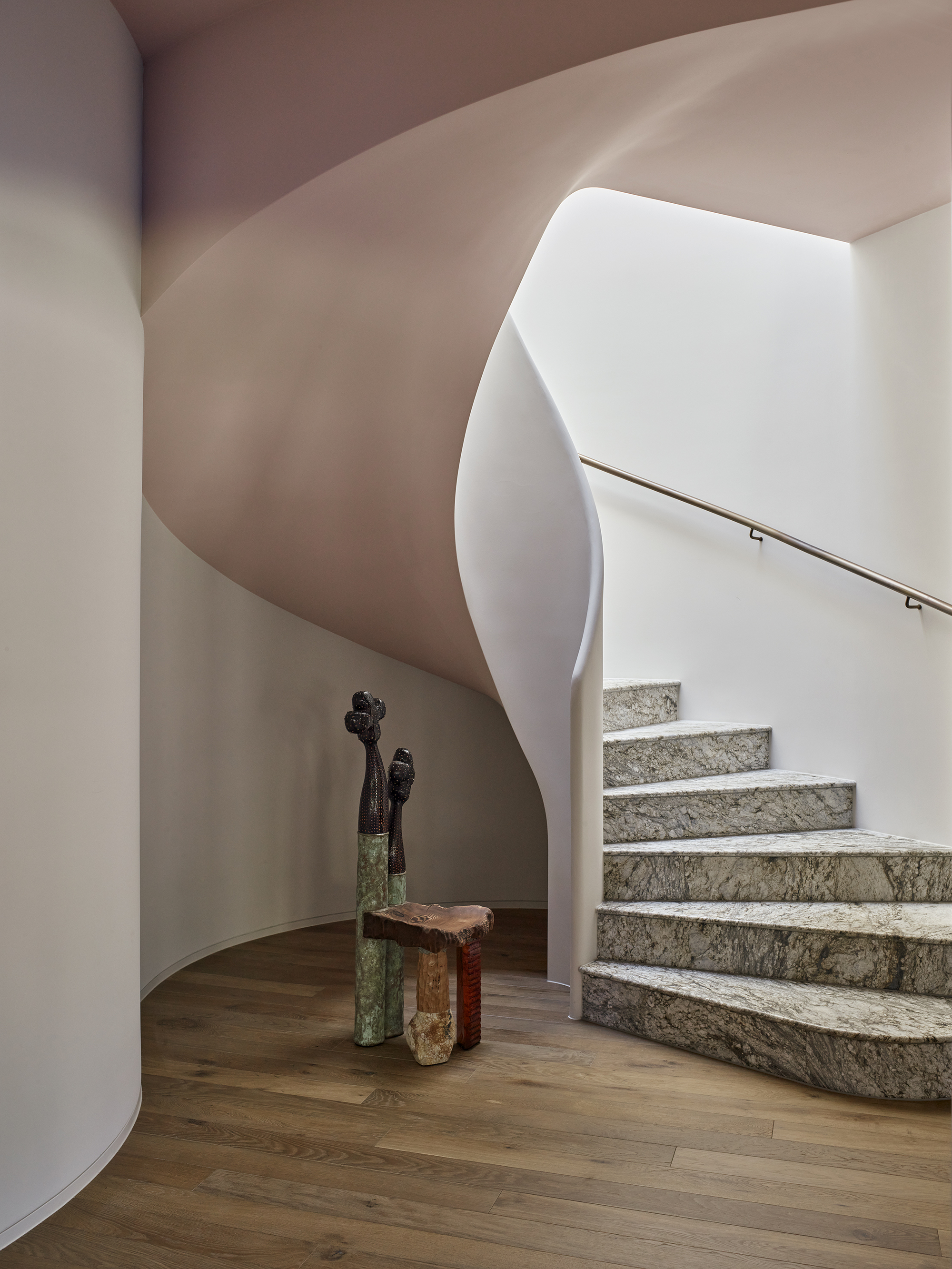 curved staircase with pink ceiling, stone steps, and sculpture at the bottom of the stairs