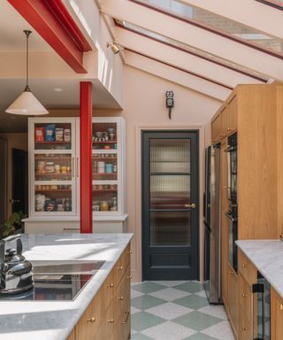 kitchen with blush walls and ceiling, red steel joist, cabinet, green and grey floor tiles, wood cabinetry, island