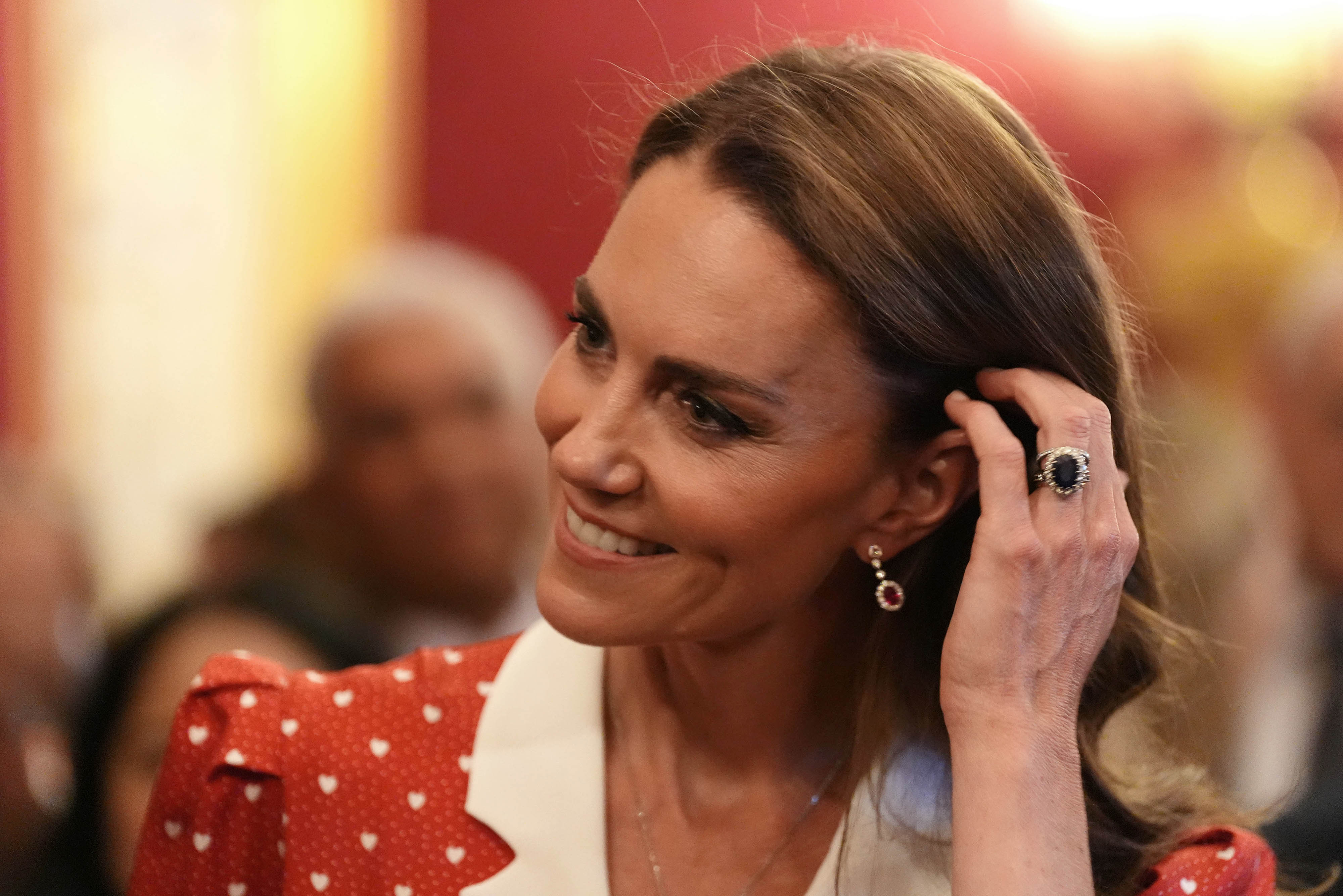 Princess Kate putting her hand in her hair and smiling