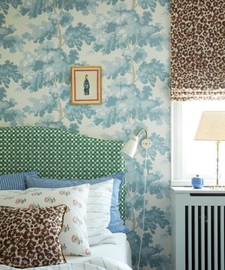 blue and white wallpapered bedroom with a leopard print window blind and layered throw pillows