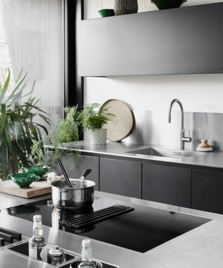 Monochrome kitchen with steel worktops and black cabinets by Roundhouse
