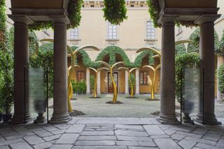 A courtyard area with large pillars on the perimeter and golden branch style pylons in the courtyard