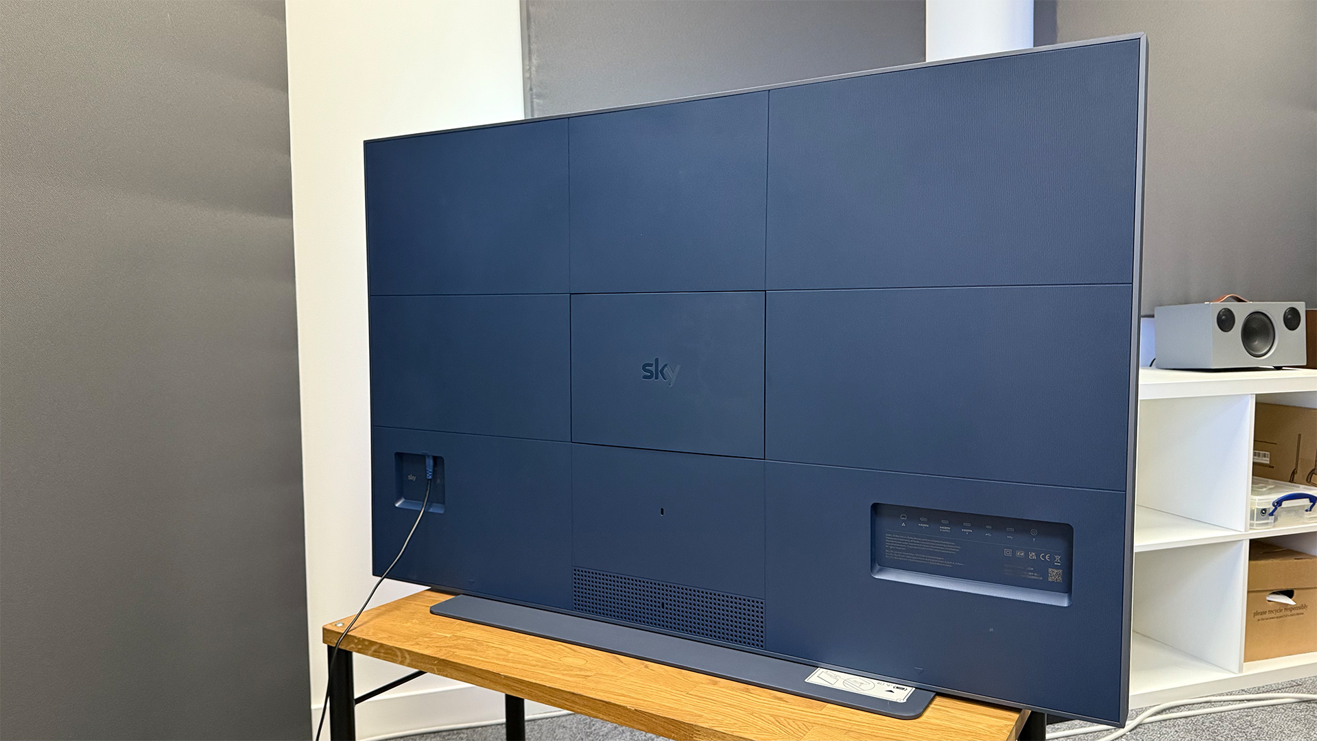 Sky Glass Gen 2 TV, soundbar and streaming service on wooden AV rack showing rear of TV set
