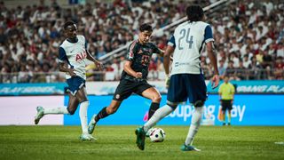 Aleksandar Pavlovic, in black shorts and shirt, dribbles through the Spurs lines in the Tottenham vs Bayern Munich live stream.