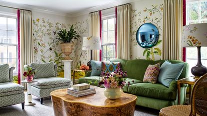 A living room with patterned floral wallpaper, a green sofa, and two patterned armchairs