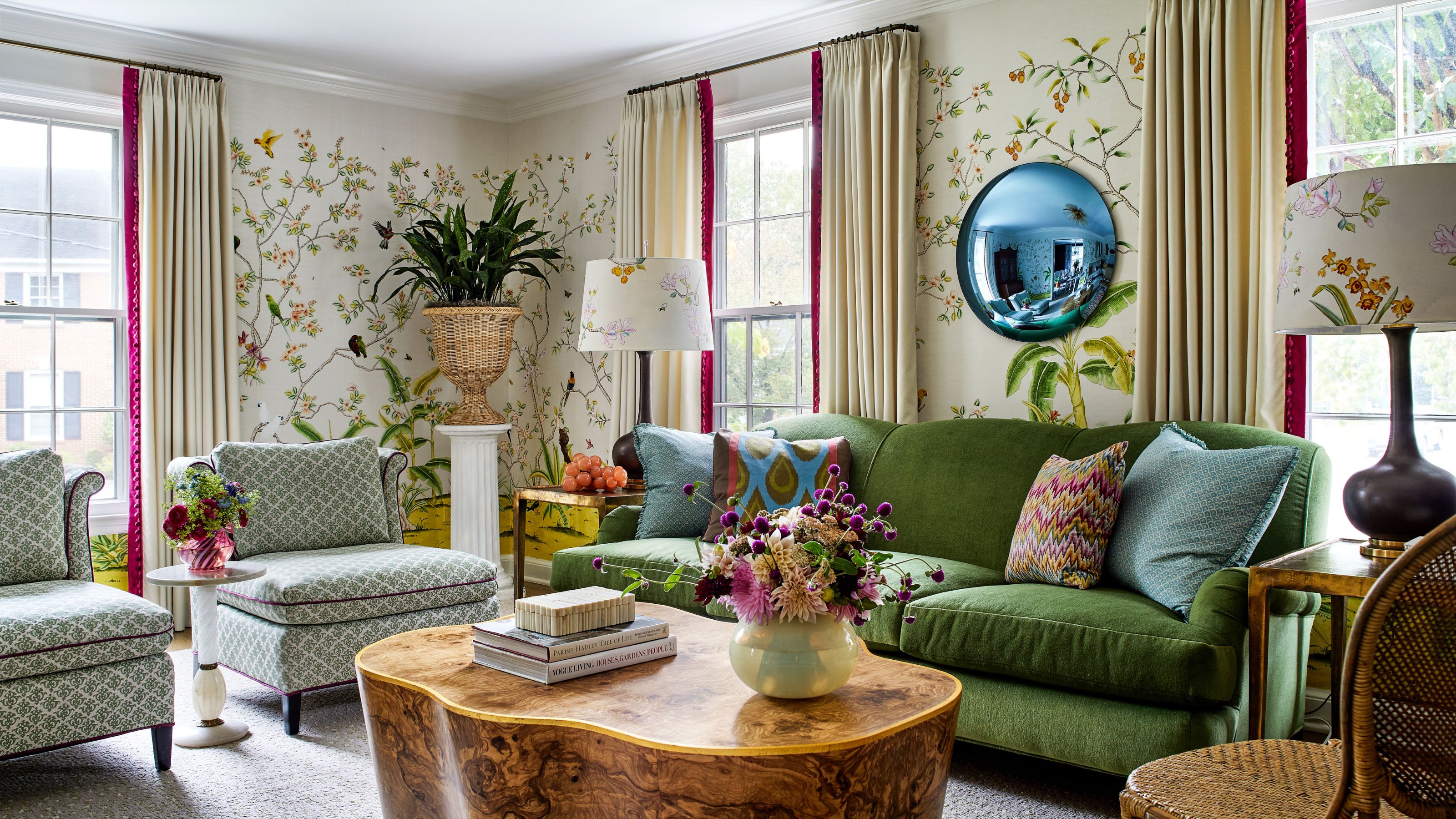 A living room with patterned floral wallpaper, a green sofa, and two patterned armchairs