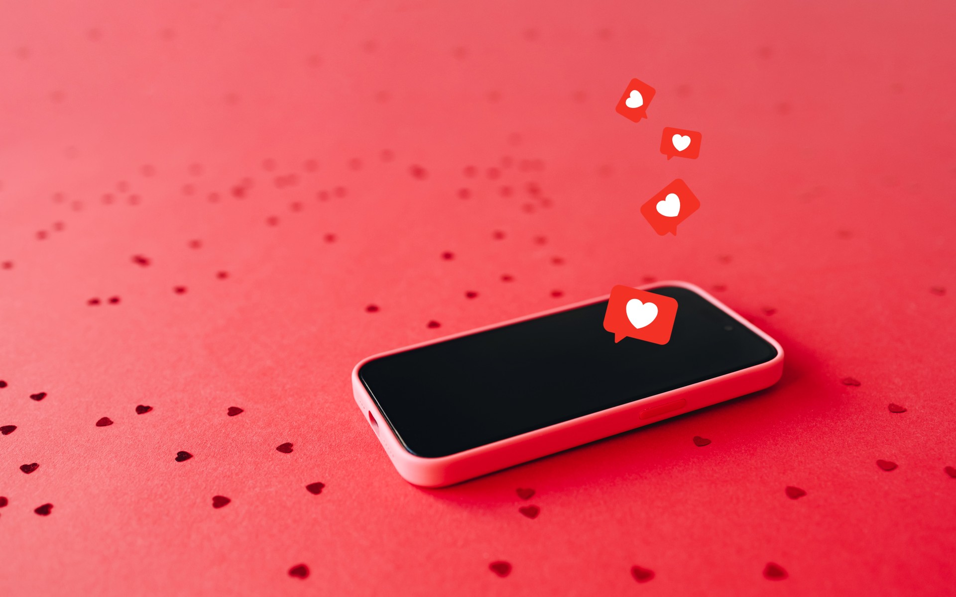 Smartphone on red background with heart confetti and like icons
