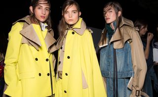 Models wear yellow trench coats, and denim and brown jacket